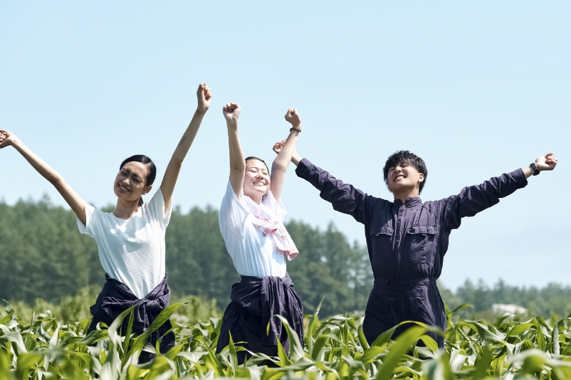 畑で両手を上げている3人